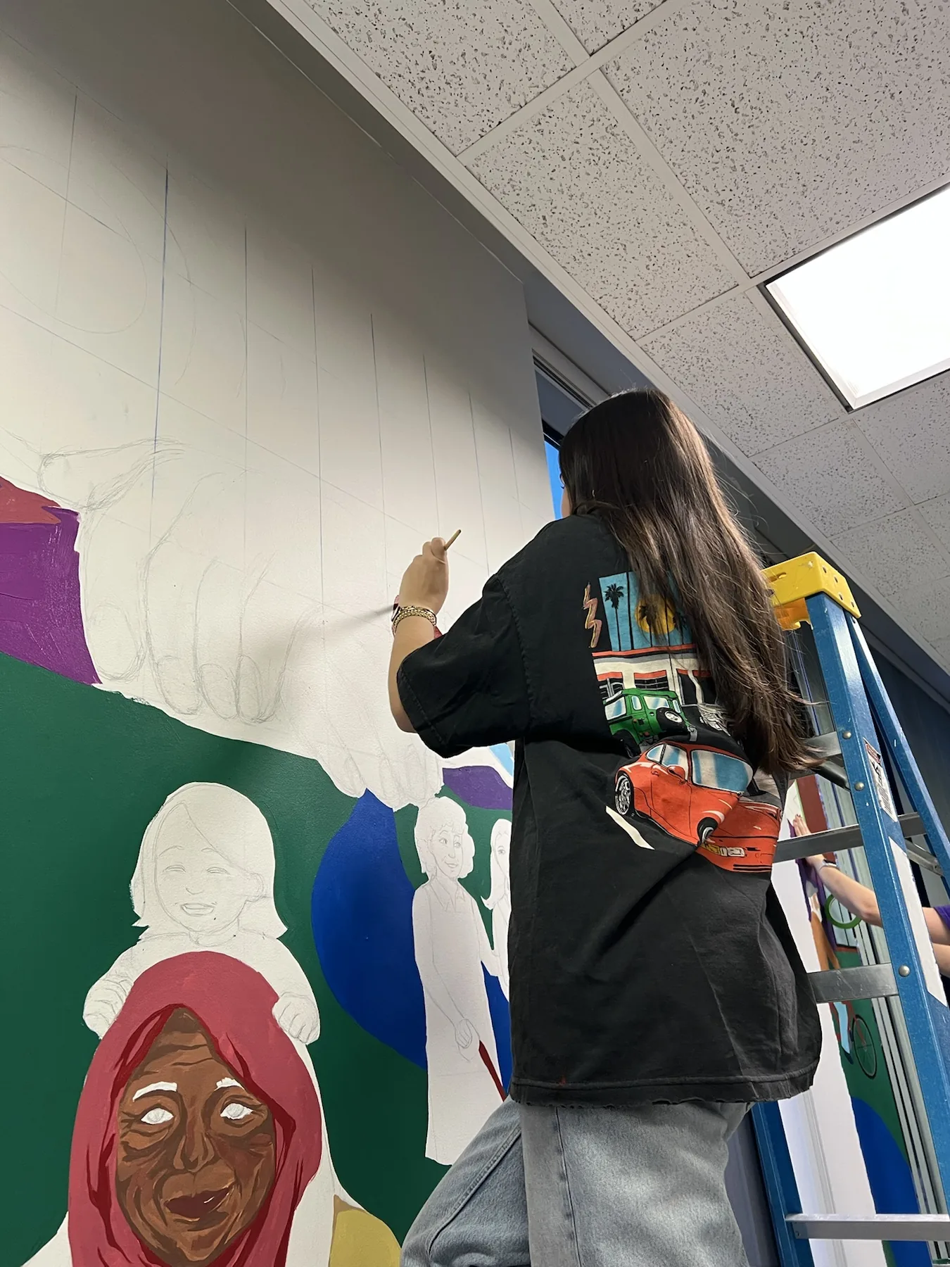 Leigh painting a large collaborative mural