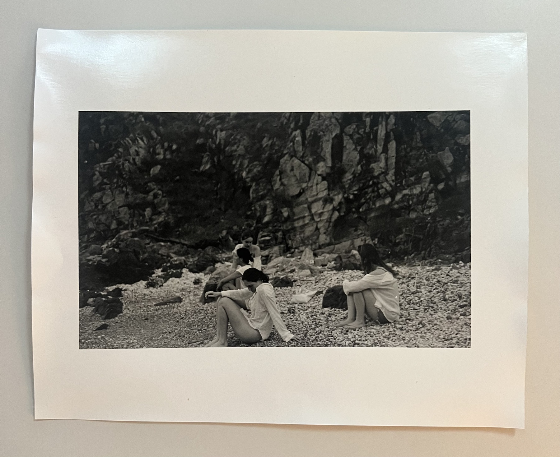 Monochrome photograph of people beside a rocky wall