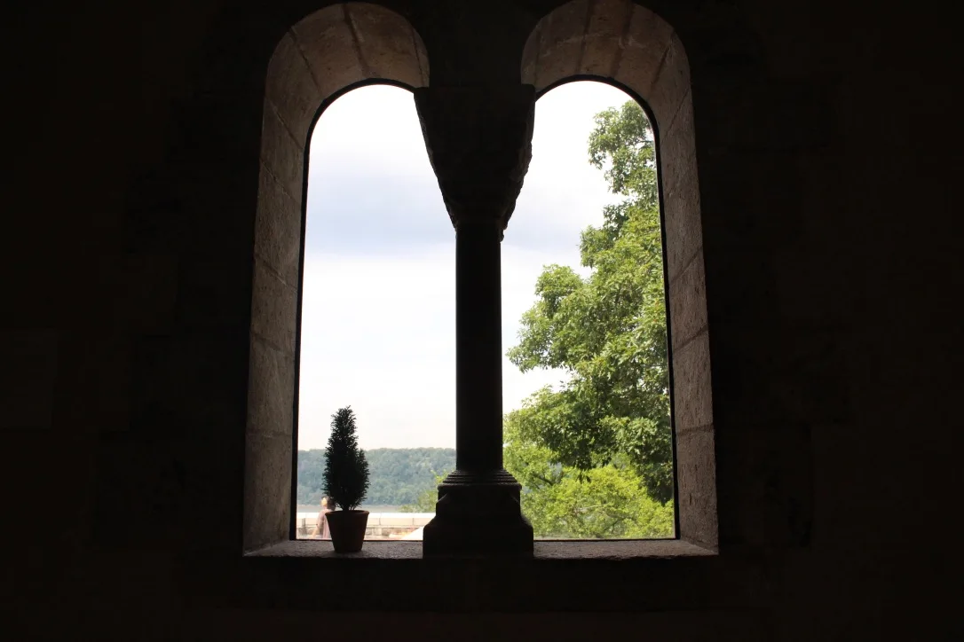 Arched stone window framing a tree and distant landscape