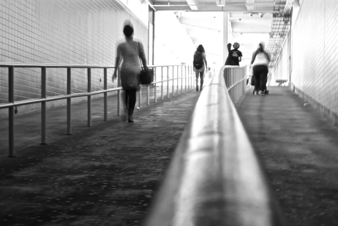 Monochrome photograph of pedestrians walking along a ramp