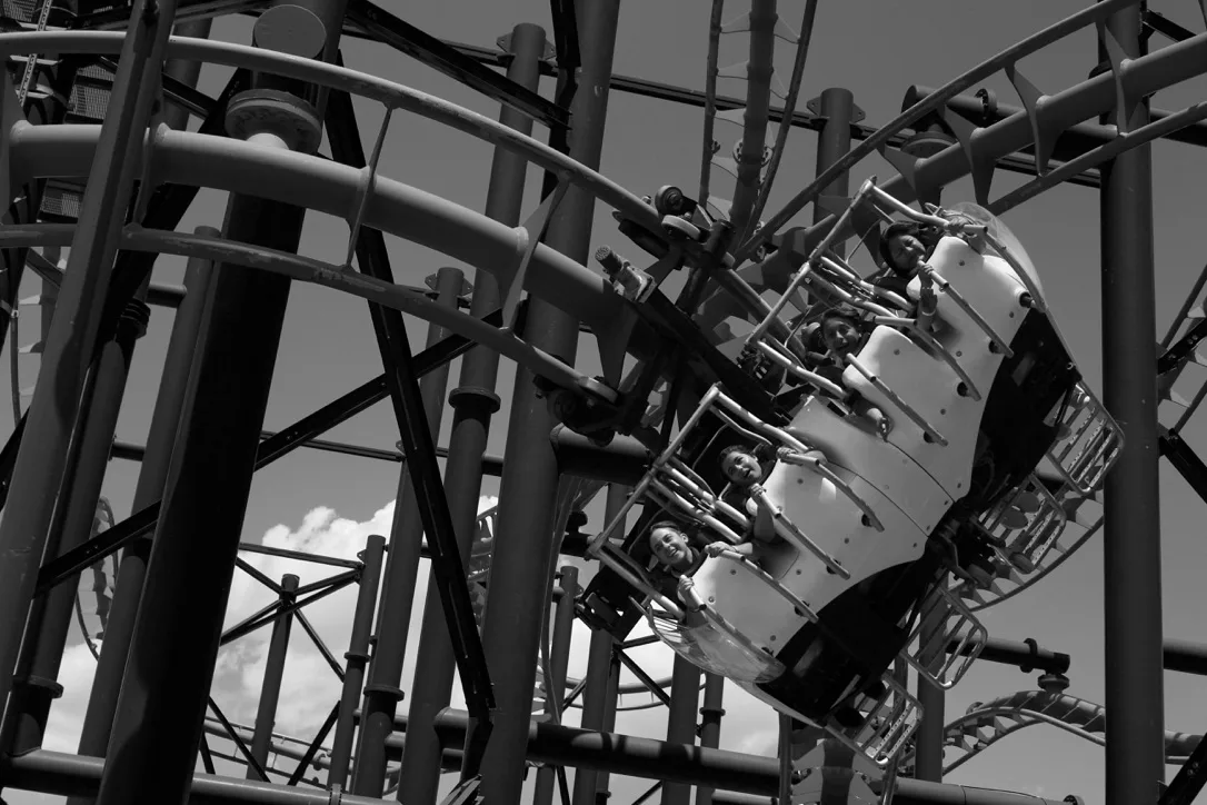 Monochrome photograph of riders on a roller coaster